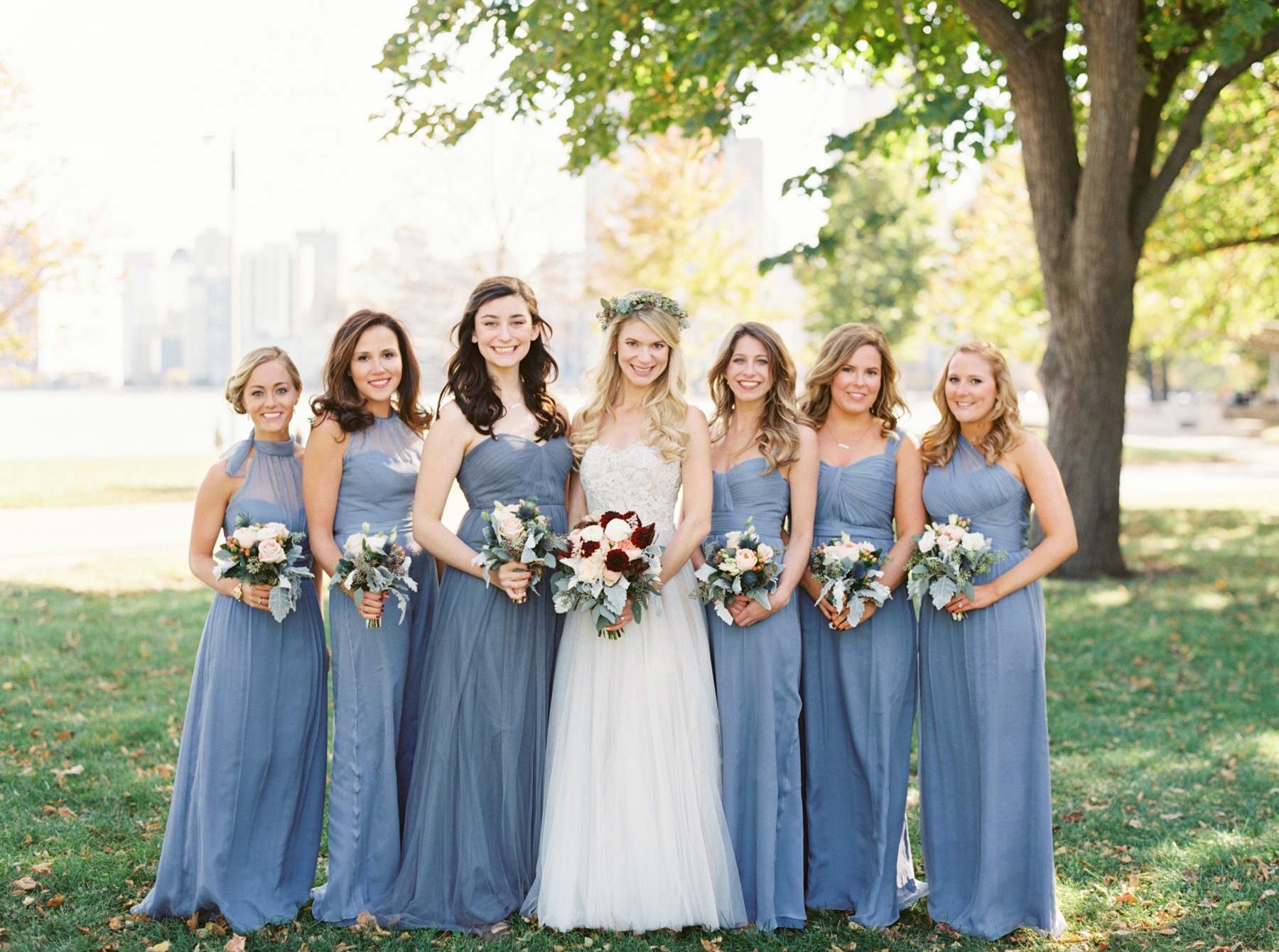 bride and bridesmaids pose with Chicago skyline background. Captured by Chicago Wedding Photographer