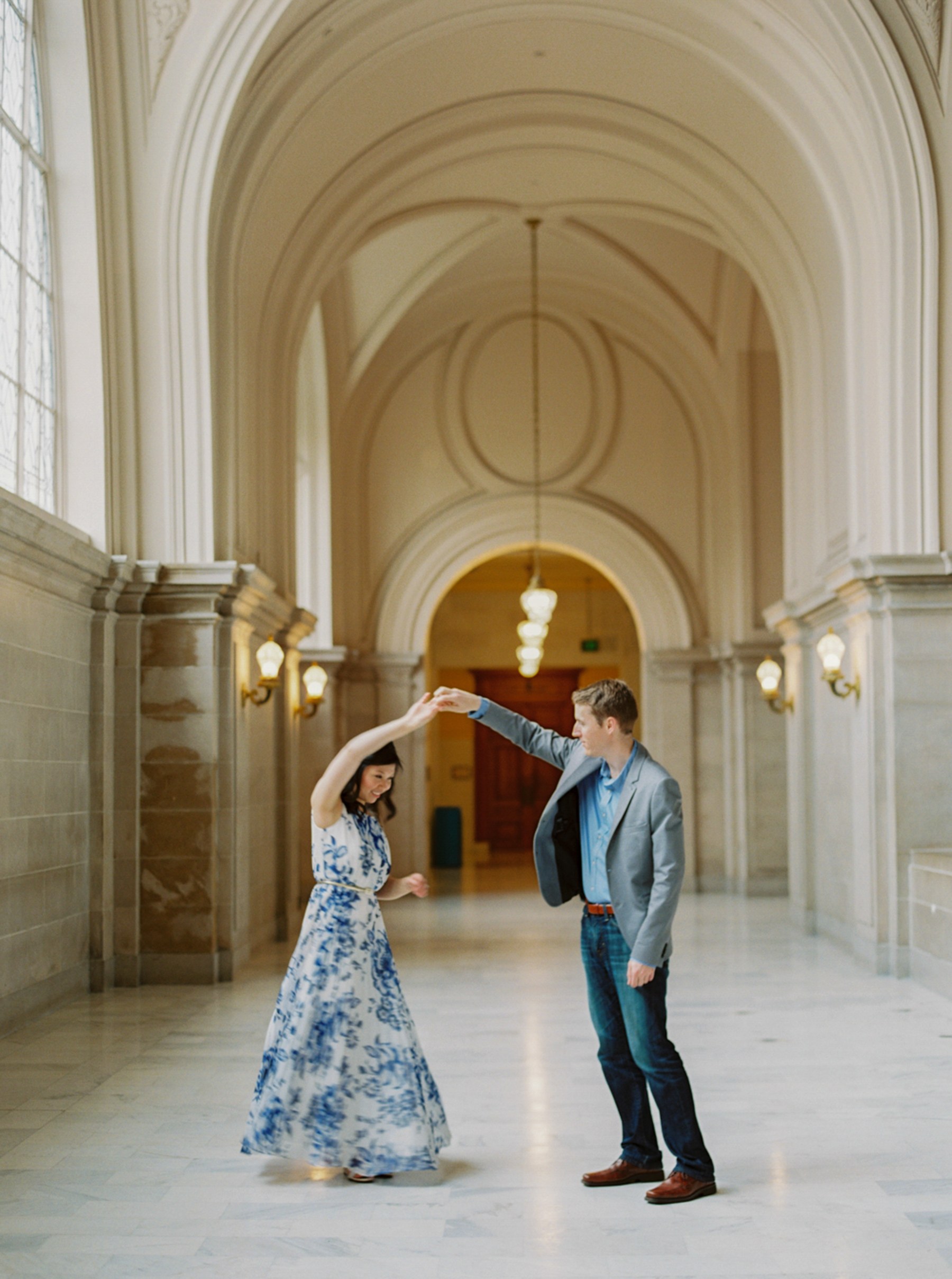 man twirling woman wearing blue & white gown during San Francisco City Hall Engagement Session