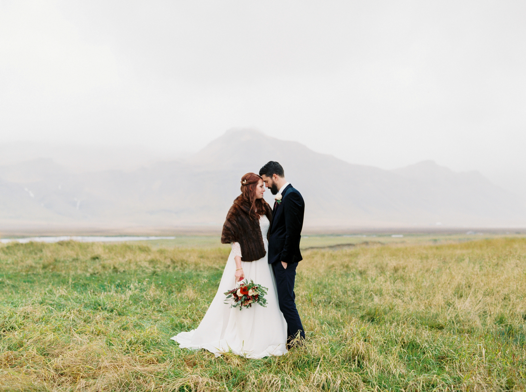 bride wearing brown fur wrap while embracing groom in Iceland