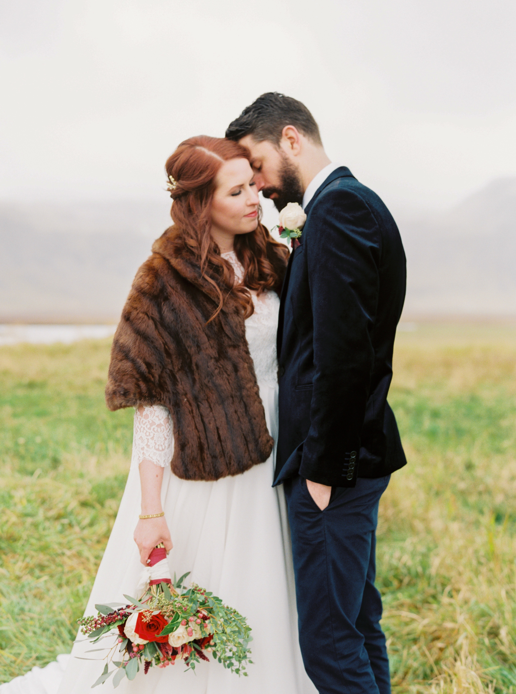 intimate photo of groom and bride wearing a fur wrap in Iceland before wedding 
