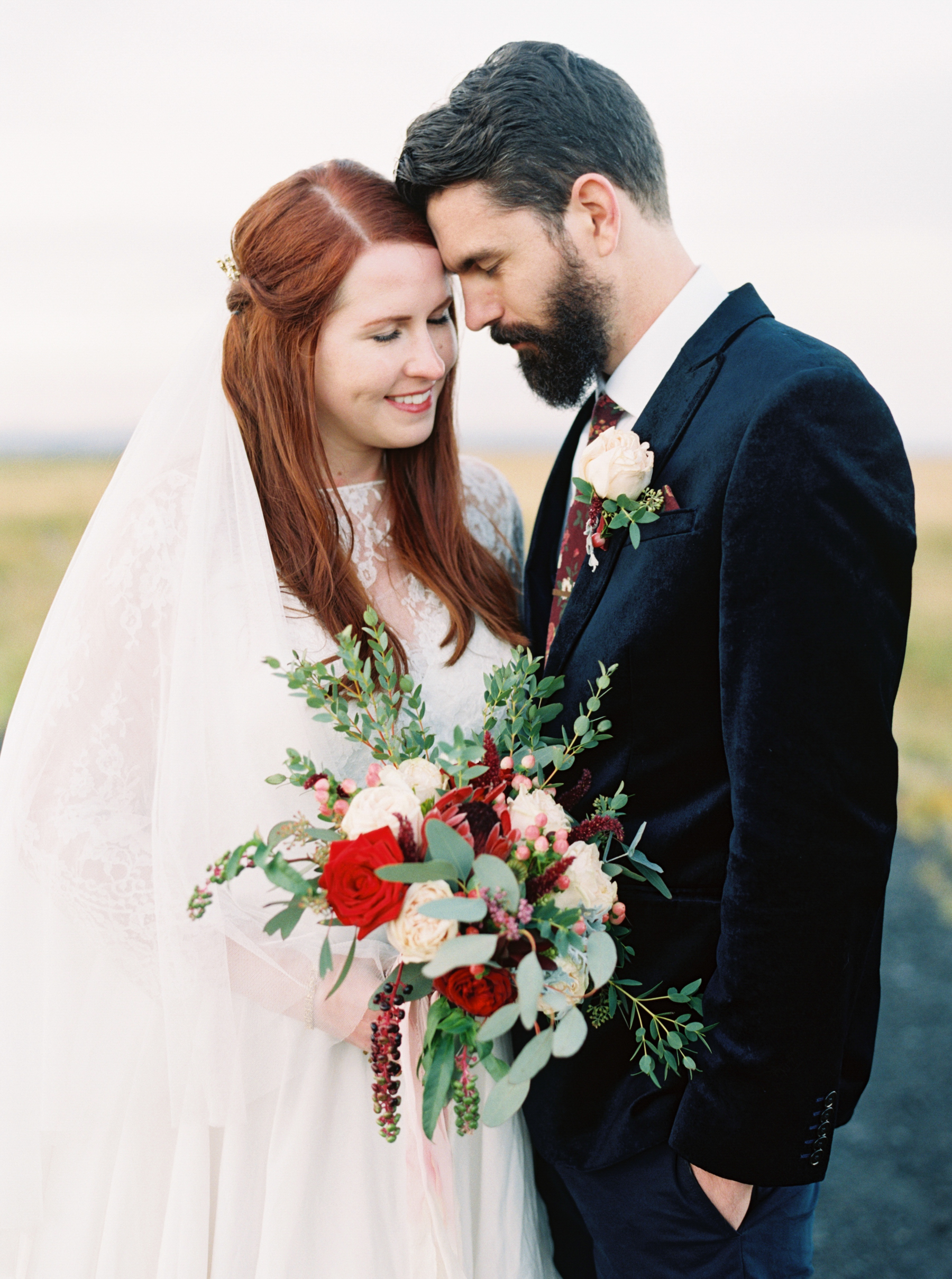 Iceland Wedding At Hotel Budir & the Black Church bride holding bouquet with red roses and greenery