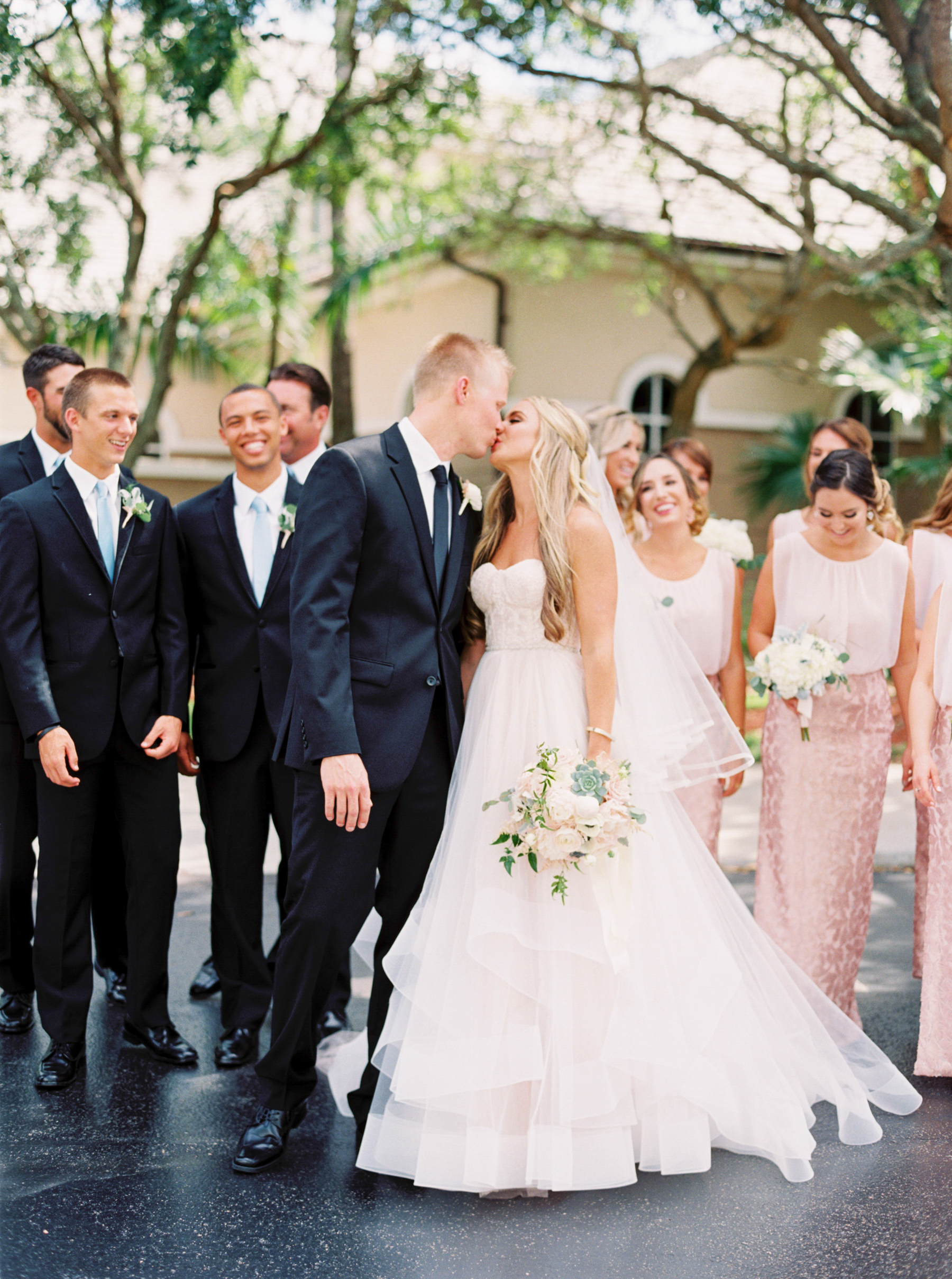 bride and groom kiss with bridal party behind them at Naples Florida Wedding 