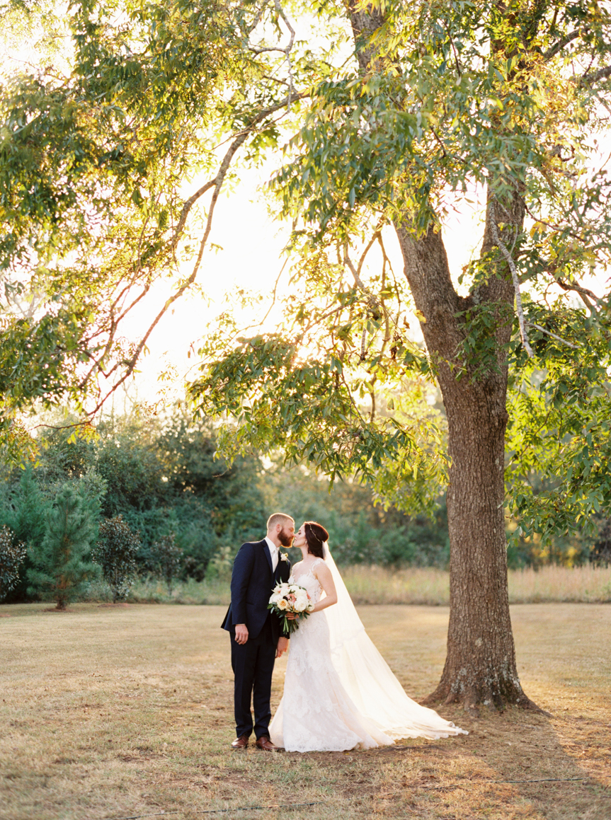 bride and groom kissing under big tree at Georgia wedding