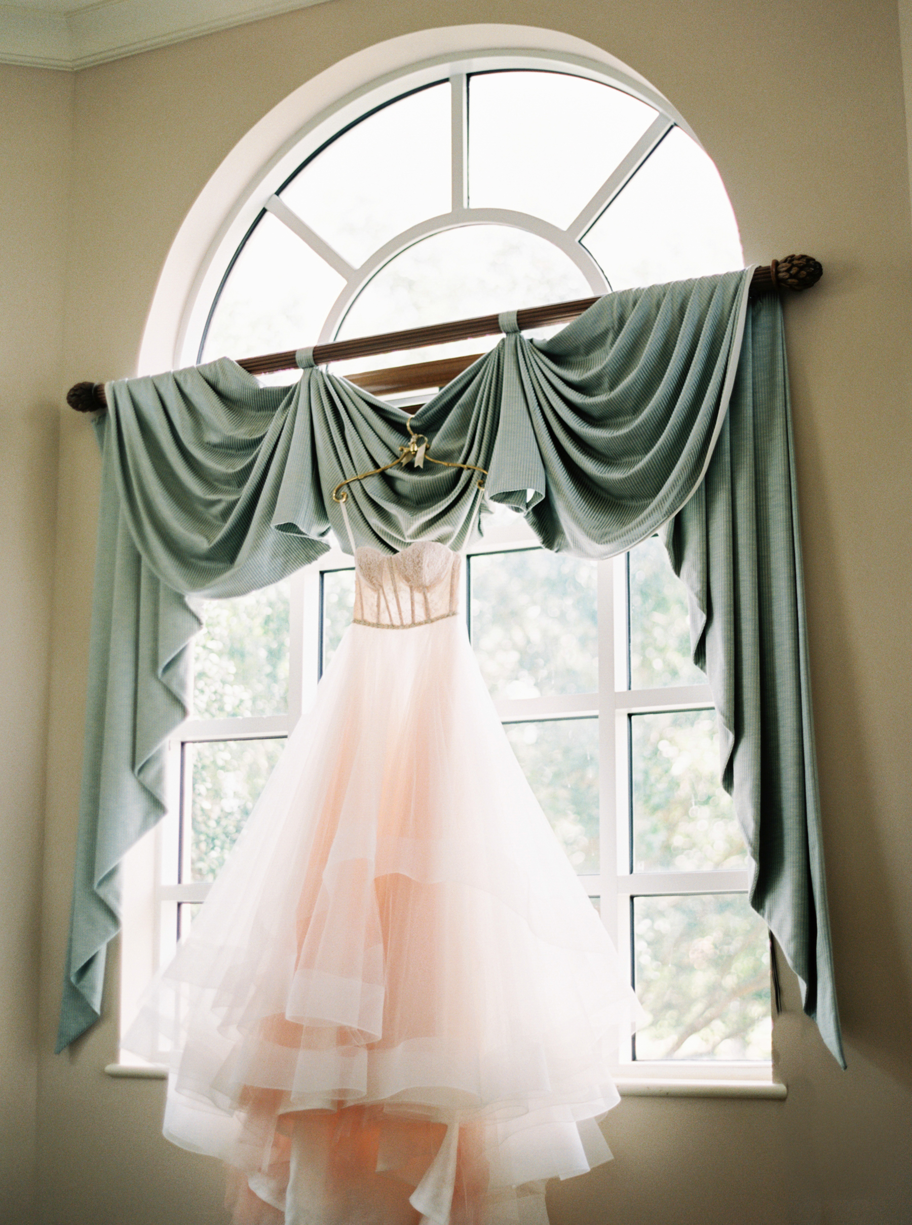 wedding dress hanging in front of large window at Naples Florida Wedding